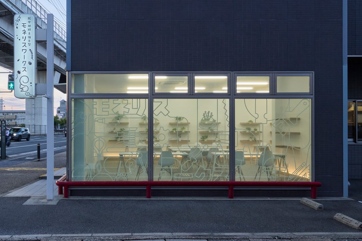 夕暮れに室内の灯りがともる、ガラス張りの建物